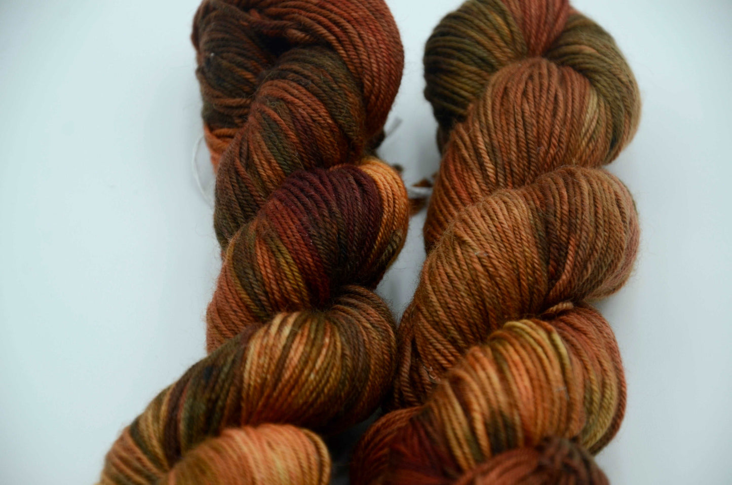 warm toned orange hand painted and hand dyed knitting yarn with dark army green notes