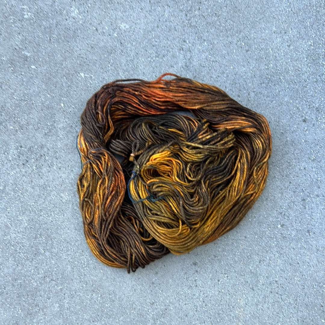 dark toned hand painted and hand dyed knitting yarn with notes of dark olive green and golden yellow