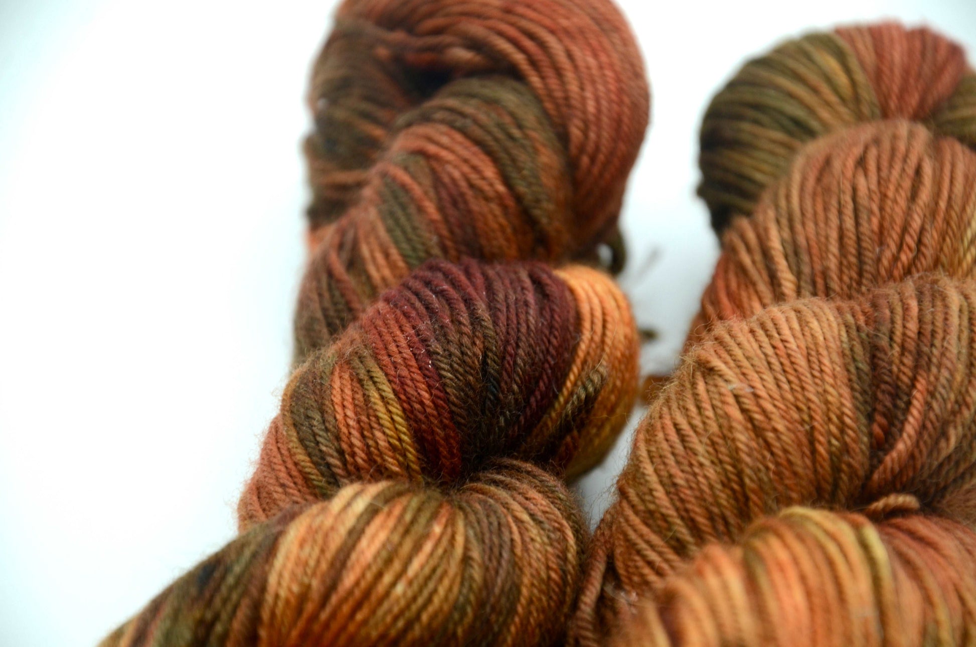 warm toned orange hand painted and hand dyed knitting yarn with dark army green notes