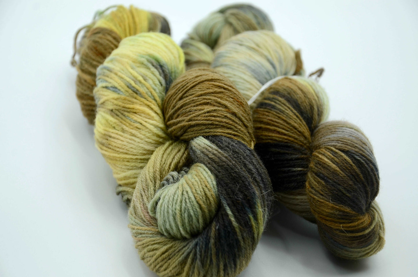 hand painted and hand dyed knitting yarn with notes of dark olive green, bright yellow and gray