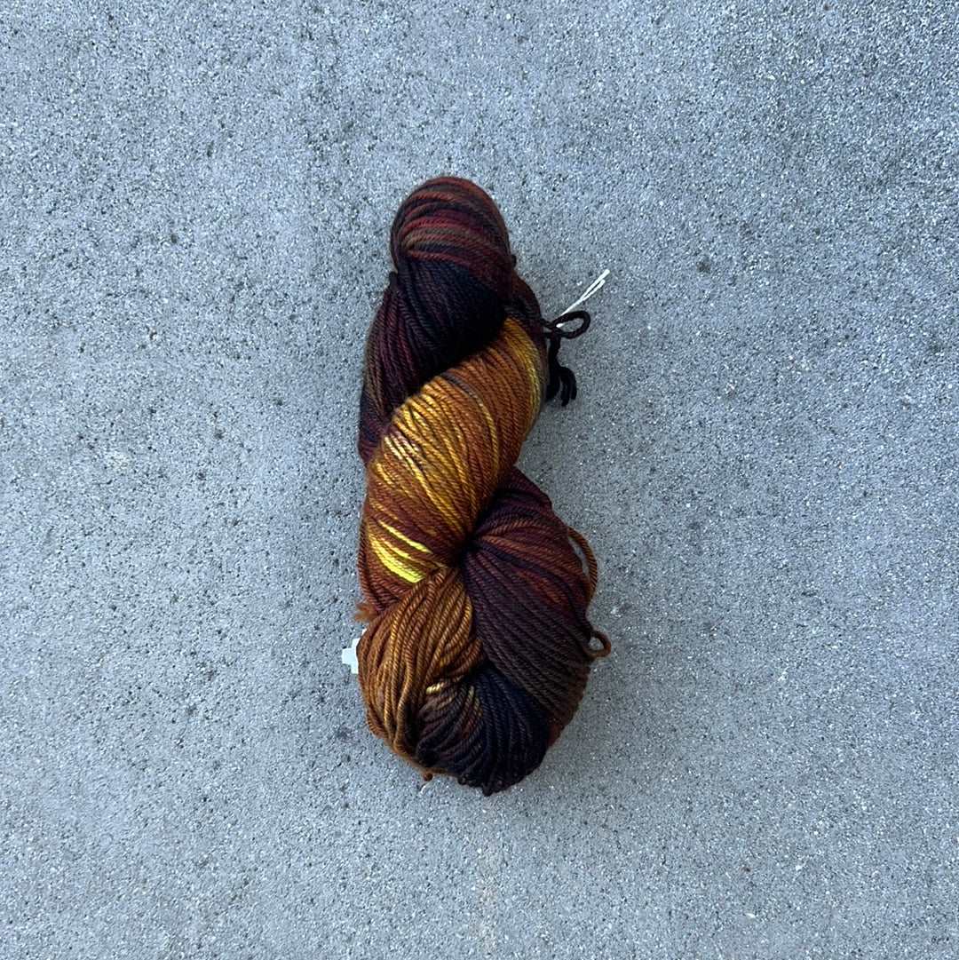 dark toned hand dyed and hand painted knitting yarn with notes of yellow and Burgundy