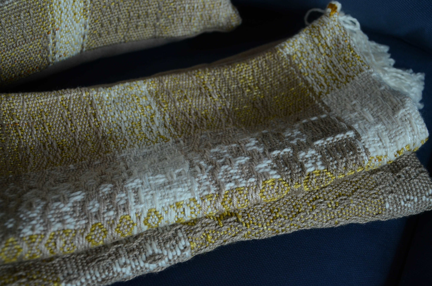 Neutral cream colored throw pillow cover on couch with tassels and golden yellow weaving detail