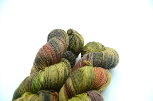 sage green hand dyed and hand painted knitting yarn with notes of orange and dark army green
