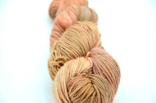 Coral colored hand painted and hand dyed knitting yarn with beige tones