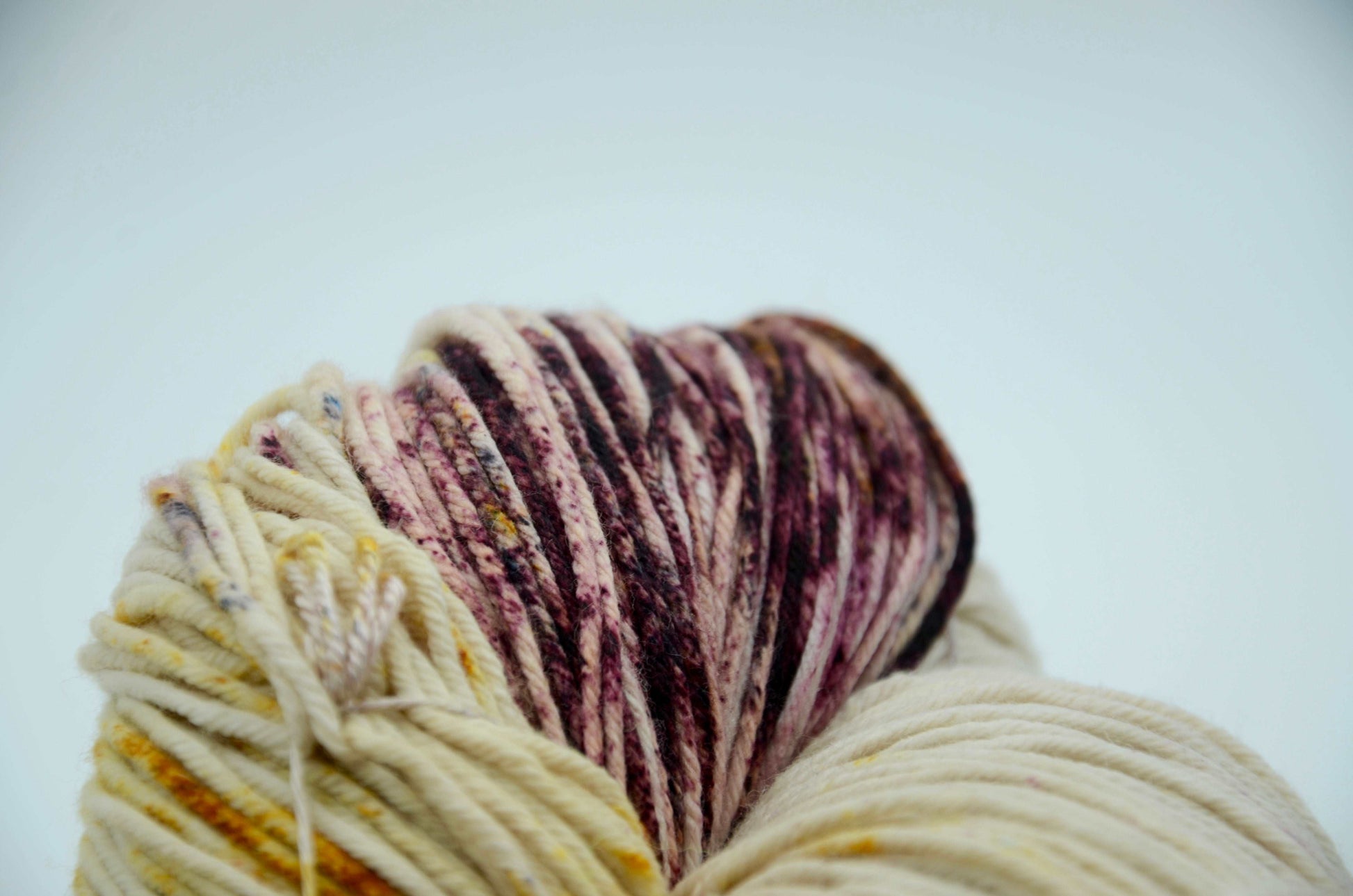 neutral toned hand dyed and hand painted knitting yarn with speckles of yellow and burgandy