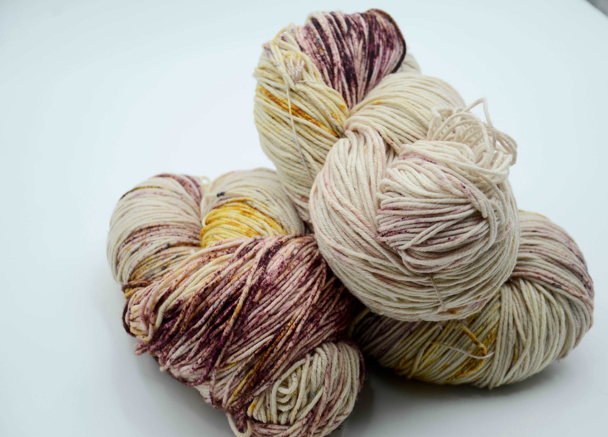 neutral toned hand dyed and hand painted knitting yarn with speckles of yellow and burgandy