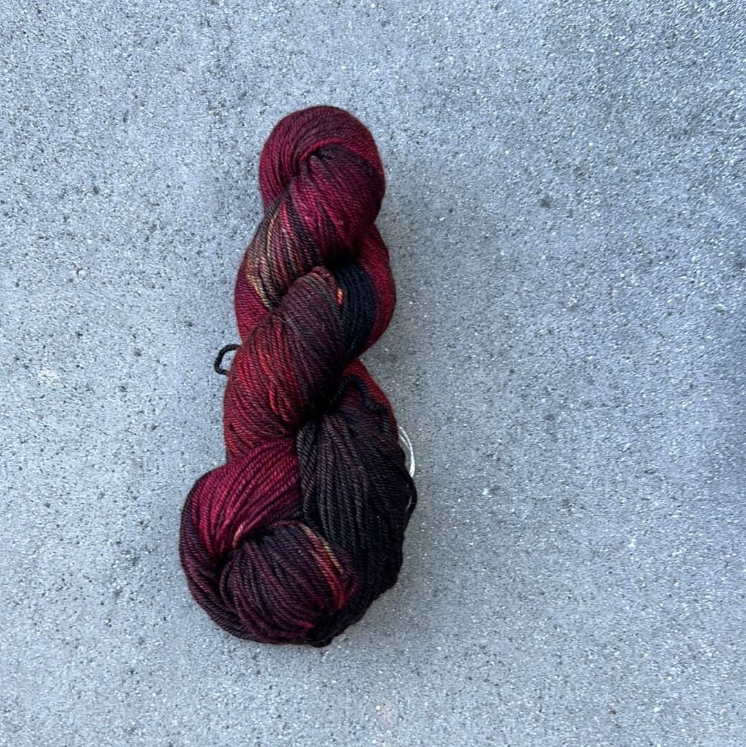 dark toned red colored hand painted and hand dyed knitting yarn with notes of yellow and dark pink