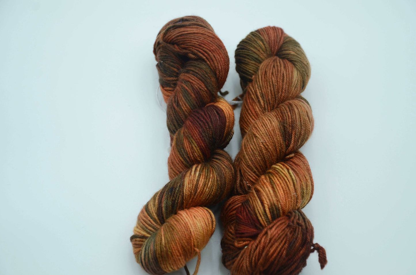 warm toned orange hand painted and hand dyed knitting yarn with dark army green notes