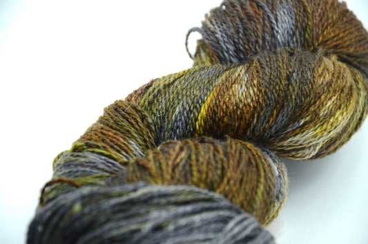 hand dyed and hand painted knitting yarn with tones of gray, dark army green and golden yellow