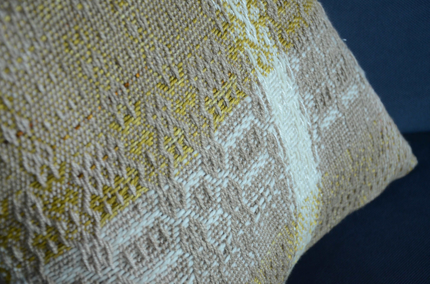 Neutral cream colored throw pillow cover on couch with tassels and golden yellow weaving detail