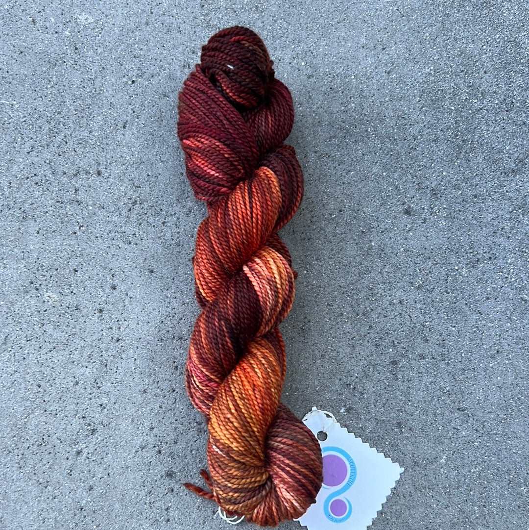 hand dyed and hand painted knitting yarn with notes of pink, orange and dark red