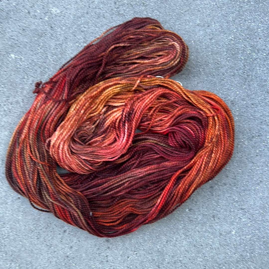 hand dyed and hand painted knitting yarn with notes of pink, orange and dark red