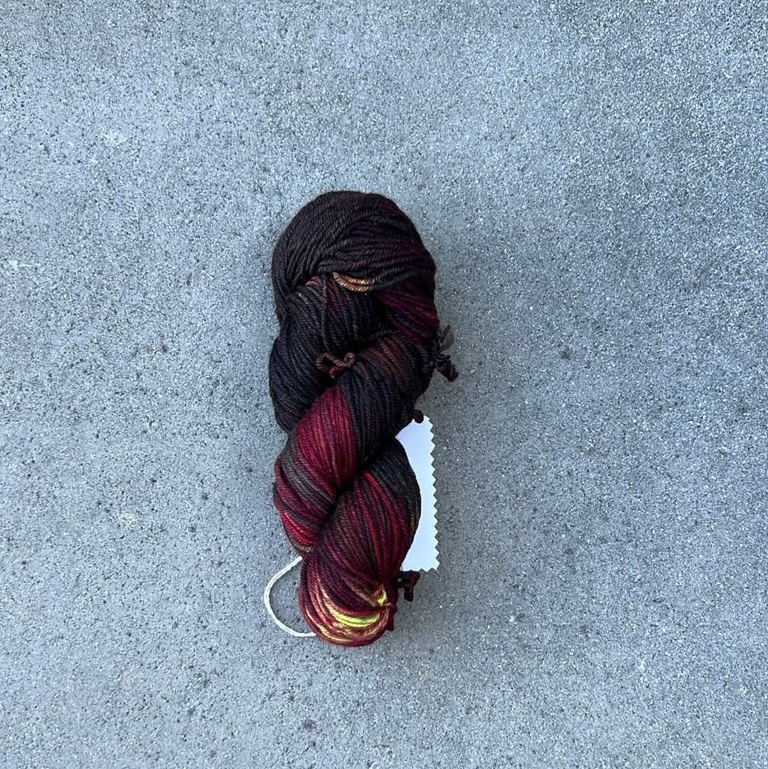 dark toned red colored hand painted and hand dyed knitting yarn with notes of yellow and dark pink