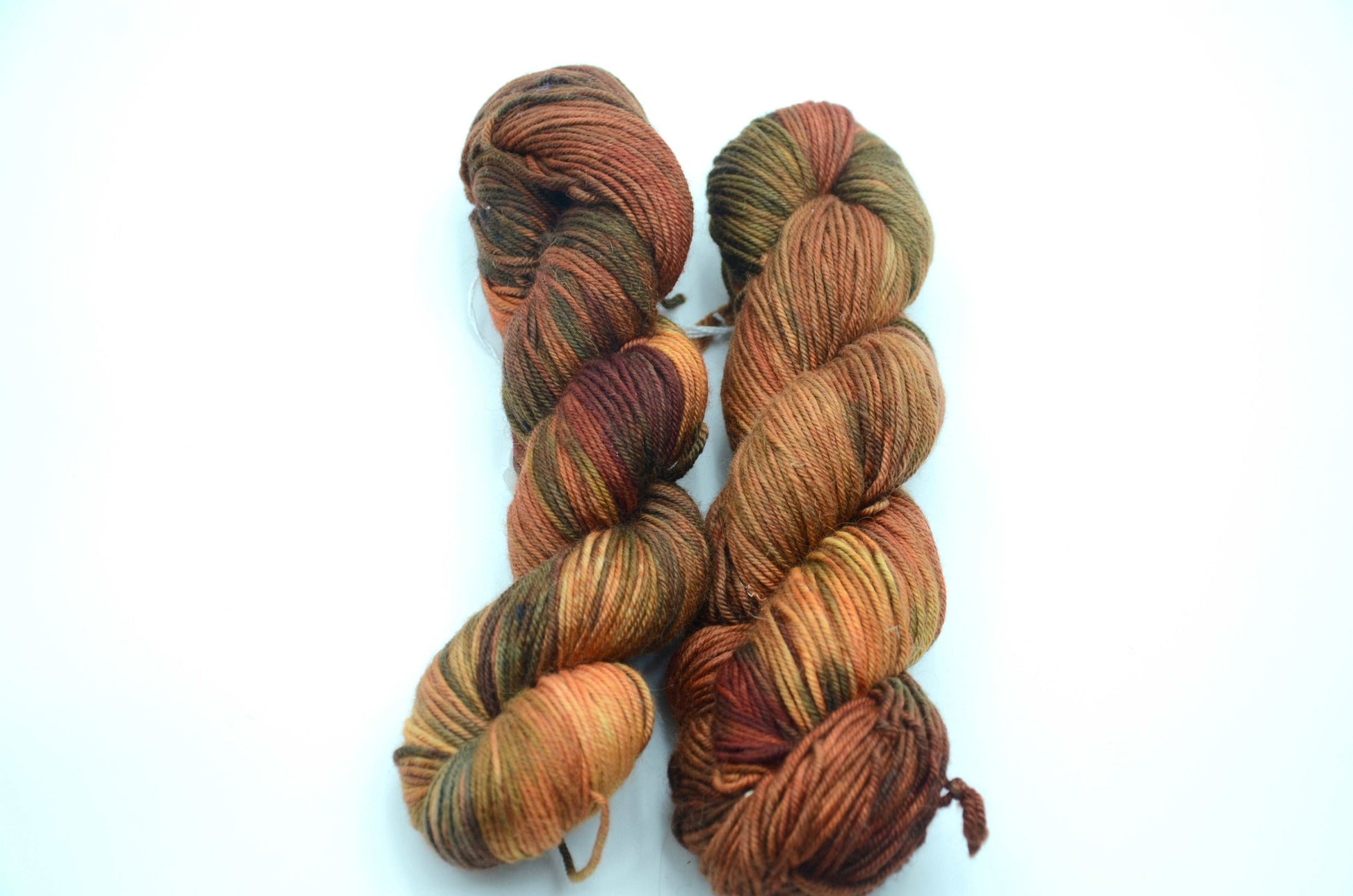 warm toned orange hand painted and hand dyed knitting yarn with dark army green notes