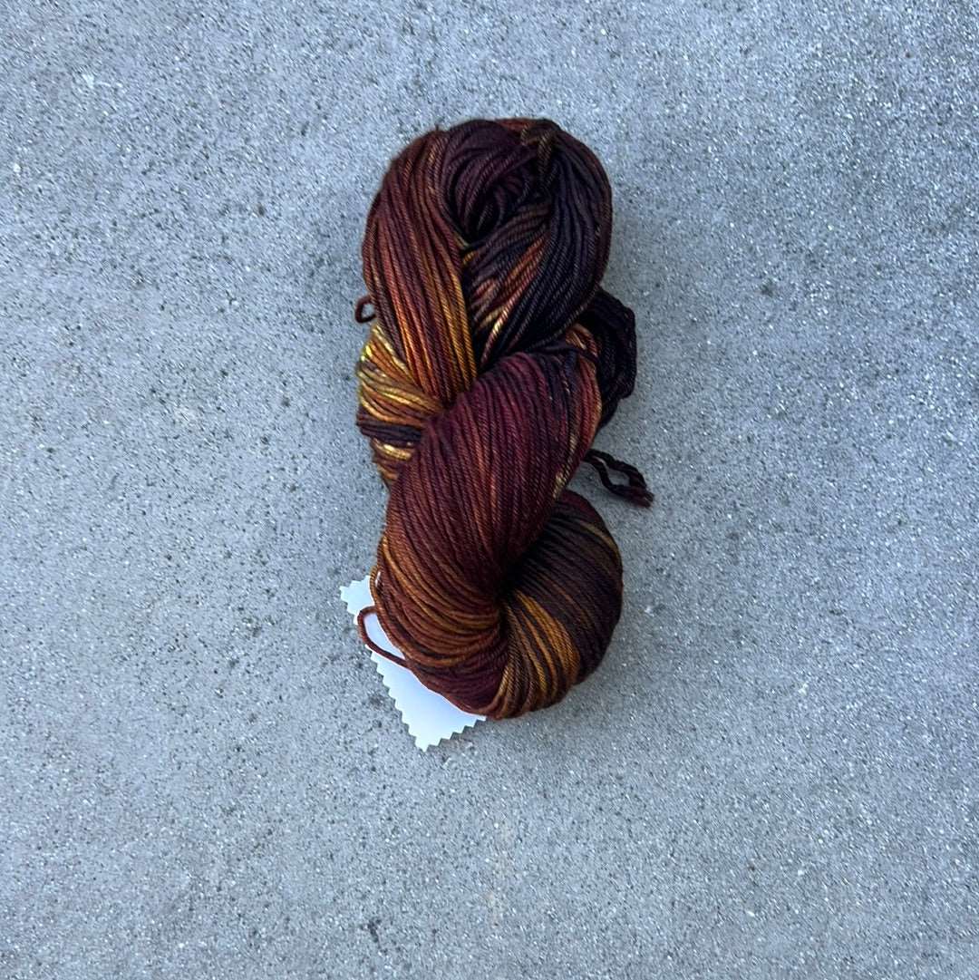 dark toned hand dyed and hand painted knitting yarn with notes of yellow and Burgundy