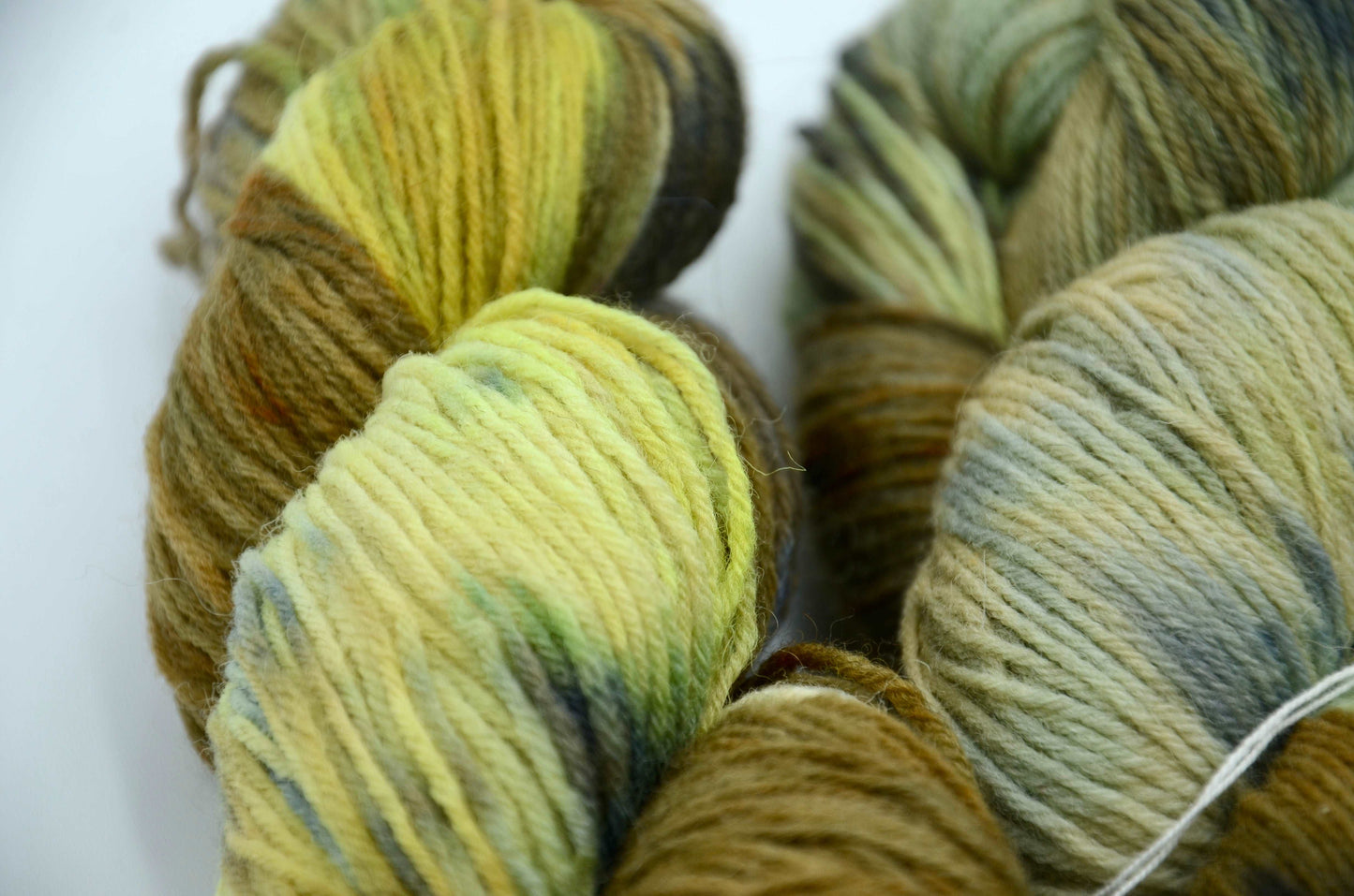 hand painted and hand dyed knitting yarn with notes of dark olive green, bright yellow and gray