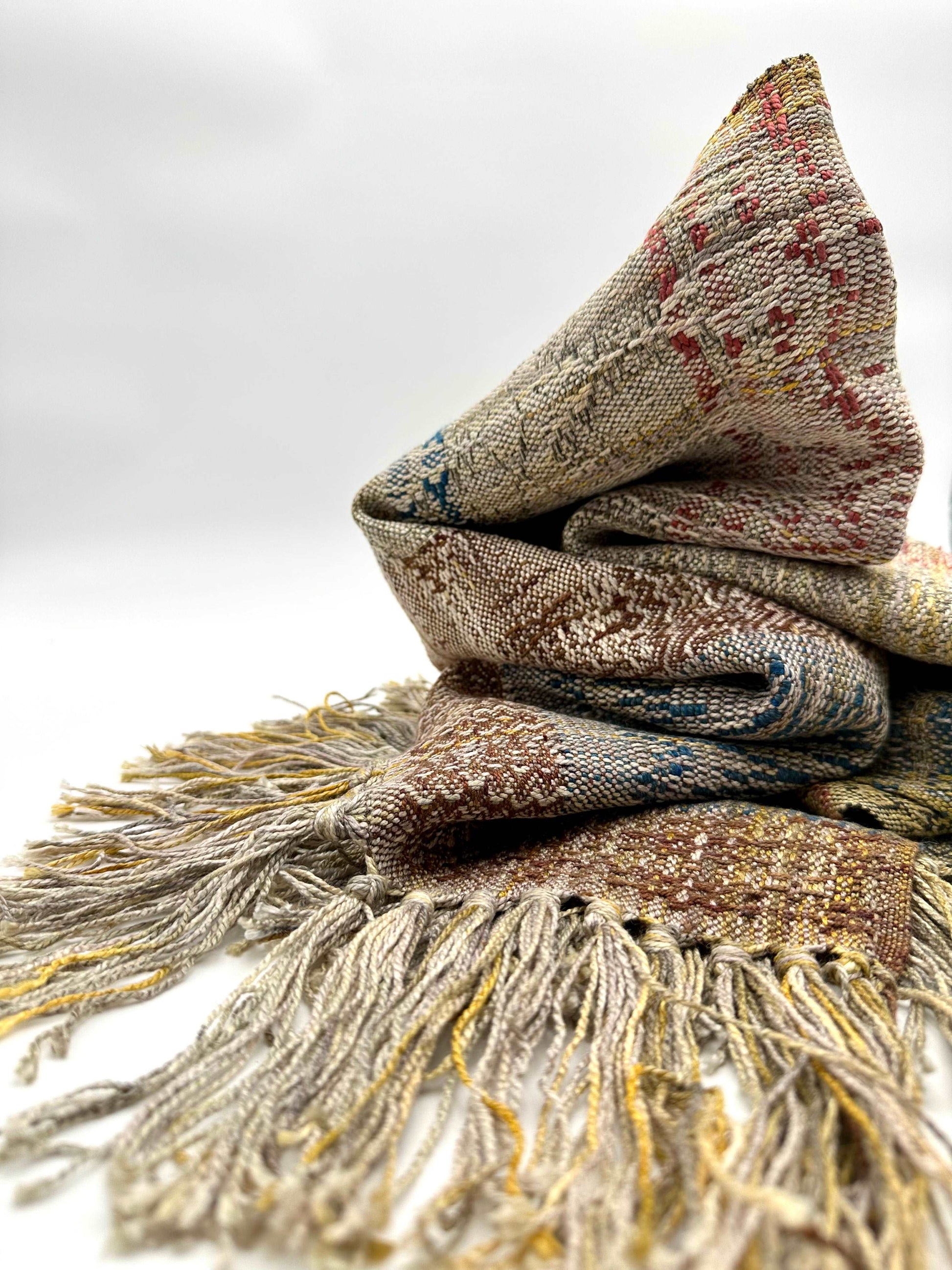 neutral colored womens handwoven scarf with notes of blue, red and yellow