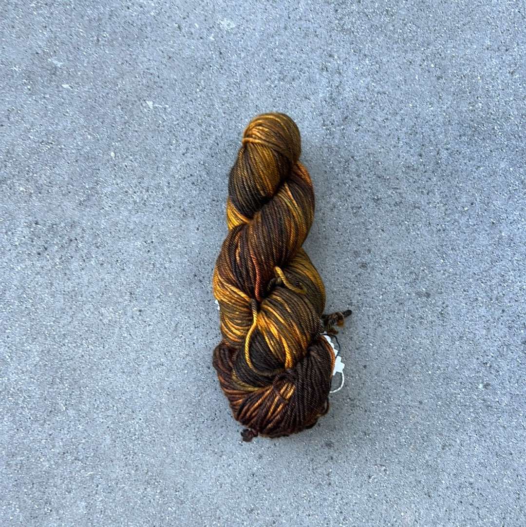 dark toned hand painted and hand dyed knitting yarn with notes of dark olive green and golden yellow