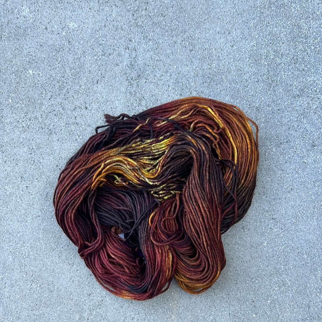 dark toned hand dyed and hand painted knitting yarn with notes of yellow and Burgundy