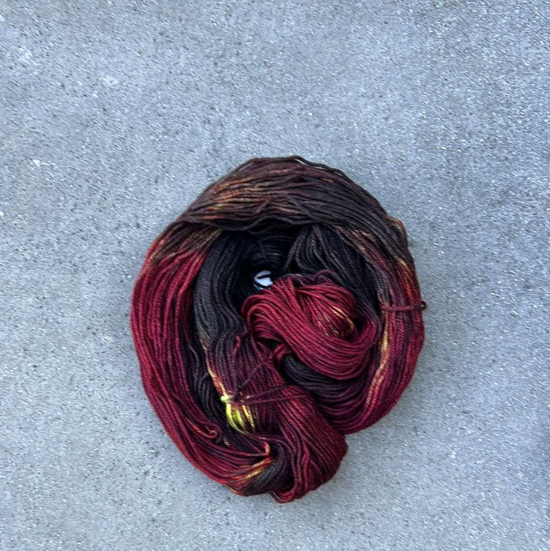 dark toned red colored hand painted and hand dyed knitting yarn with notes of yellow and dark pink