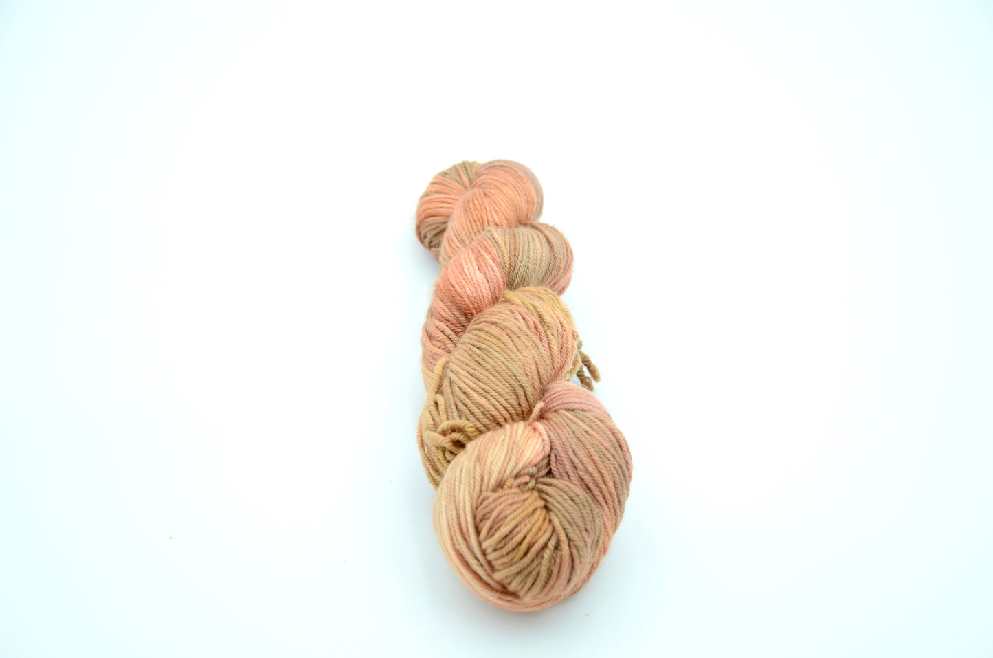 Coral colored hand painted and hand dyed knitting yarn with beige tones